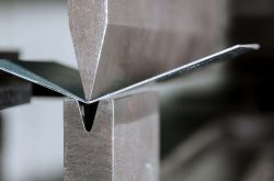 The process of bending sheet metal on a hydraulic bending machine. Metalworking plant.